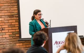 Ambar Cristina Hanson onstage speaking in front of students