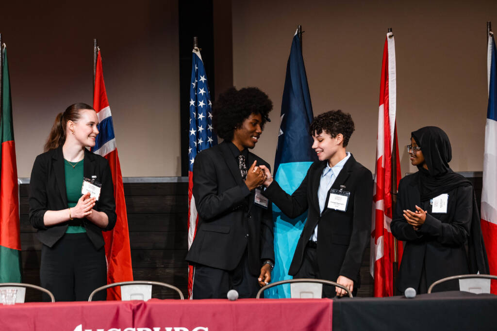 Mayors Challenge debaters congratulate one another after the debate ends.