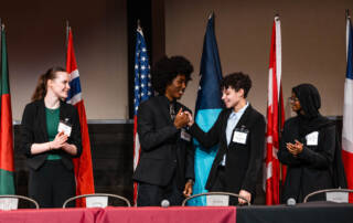 Mayors Challenge debaters congratulate one another after the debate ends.