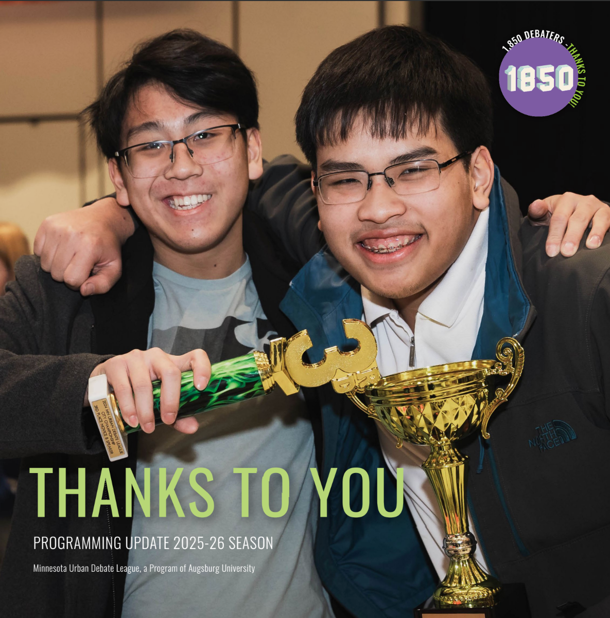 Two smiling students hold up their trophies